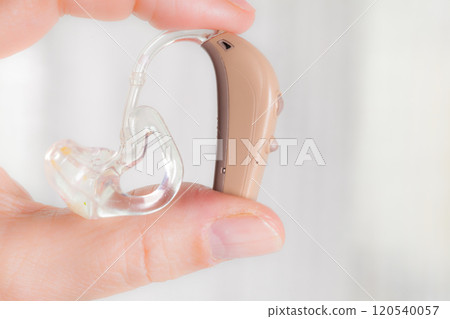 senior person holding hearing aid closeup 120540057