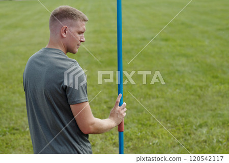 Man Preparing for Javelin Throw in Open Field 120542117