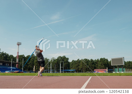Athlete Throwing Javelin in Outdoor Sports Stadium 120542138