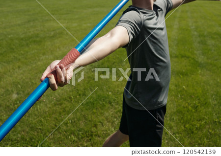 Young Athlete Preparing for Javelin Throw in Field 120542139