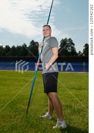 Holding Javelin on Green Field Under Party Cloudy Sky Holding Javelin on Green Field Under Party Cloudy Sky 120542162