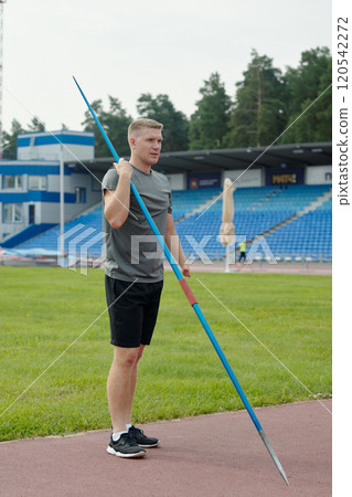 Holding Javelin on Outdoor Track with Stadium in Background Holding Javelin on Outdoor Track with Stadium in Background 120542272
