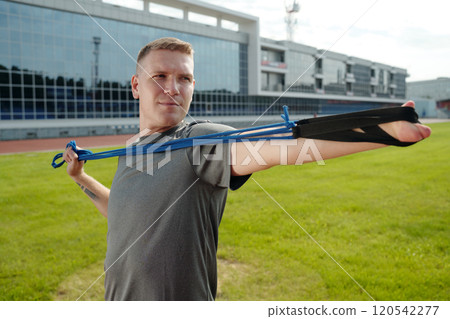 Exercising with Resistance Band on Outdoor Sports Field Exercising with Resistance Band on Outdoor Sports Field 120542277