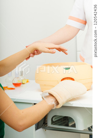 Woman getting paraffin hand treatment at beautician Woman getting paraffin hand treatment at beautician 120542436