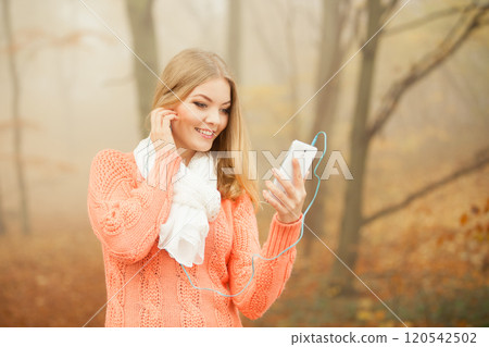 Woman with earphones listening to music in park. Woman with earphones listening to music in park. 120542502