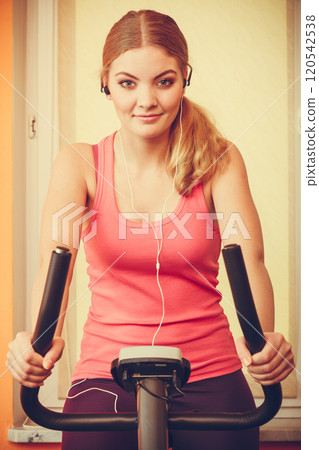 Woman on exercise bike listening music. Fitness 120542538
