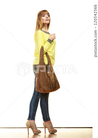 woman holds brown fringe handbag 120542566