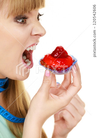 Woman holds cupcake trying to resist temptation 120542606