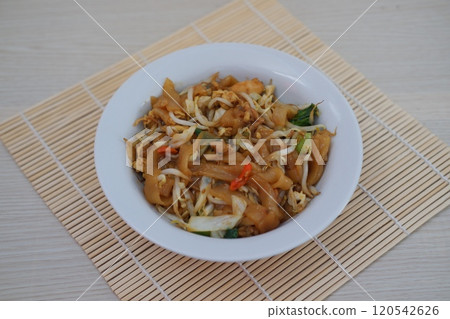 plate of stir-fried noodles with vegetables, bean sprouts, and chili slices, served on a bamboo mat plate of stir-fried noodles with vegetables, bean sprouts, and chili slices, served on a bamboo mat 120542626