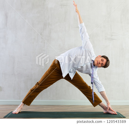 Young guy office worker doing yoga in studio Young guy office worker doing yoga in studio 120543389