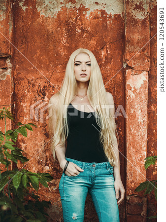 Beautiful blonde.Sexy girl in denim pants and a black t-shirt on a background of red textures. Beautiful blonde.Sexy girl in denim pants and a black t-shirt on a background of red textures. 120543691