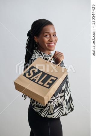 Smiling Woman Holding Shopping Bag with Sale Sign Smiling Woman Holding Shopping Bag with Sale Sign 120544429