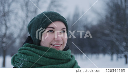 girl standing in park on winter day under snowfall 120544665