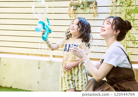 Parents and children playing with electric soap bubbles in the garden 120544704
