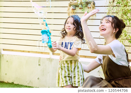 Parents and children playing with electric soap bubbles in the garden 120544706