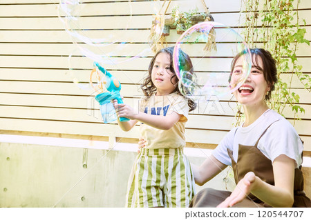 Parents and children playing with electric soap bubbles in the garden 120544707