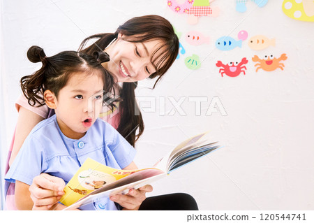 A nursery teacher reading a picture book with a child 120544741