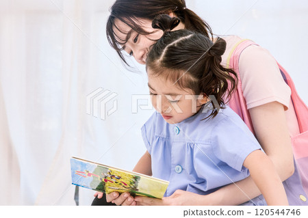 A nursery teacher reading a picture book with a child A nursery teacher reading a picture book with a child 120544746