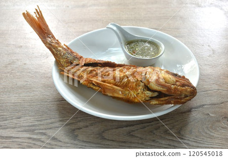 deep fried fresh red snapper fish dipping Thai spicy seafood sauce on plate 120545018
