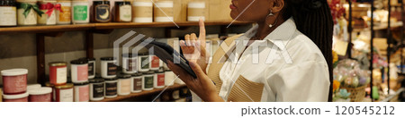 Browsing Shelf while Holding Tablet in Store 120545212