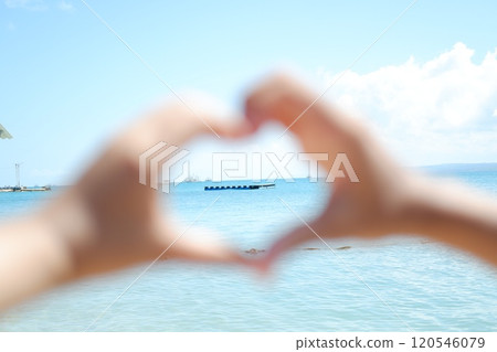 Hands forming a heart shape with the sea in the background. 120546079