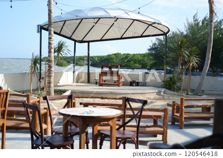 Empty tables and chairs in a restaurant on the beach with sea background 120546418