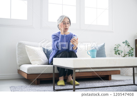 一位白髮老人拿著智慧型手機並看著螢幕的圖像,由於老花眼而很難看到。 一位白髮老人拿著智慧型手機並看著螢幕的圖像,由於老花眼而很難看到。 120547408