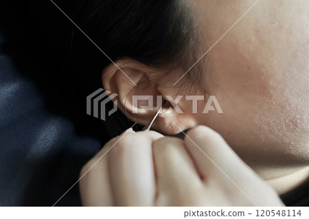 Woman cleaning her ears with a metal earpick 120548114