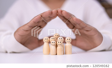 Hand of a person laying down protection a wooden dolls to show represents the protection of family safety, Insurance management planning, Health care and finance, Property and family risk reduction. Hand of a person laying down protection a wooden dolls to show represents the protection of family safety, Insurance management planning, Health care and finance, Property and family risk reduction. 120549162
