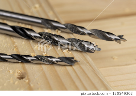 metal drill bit and pine wood board during operation 120549302