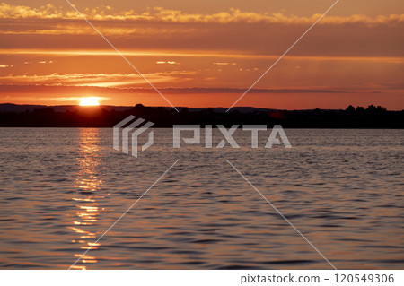 beautiful sunset with sun and orange sky on the lake 120549306