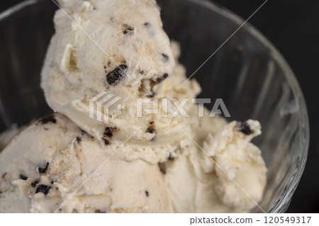 white creamy ice cream with pieces and crumbs of chocolate in a glass bowl 120549317