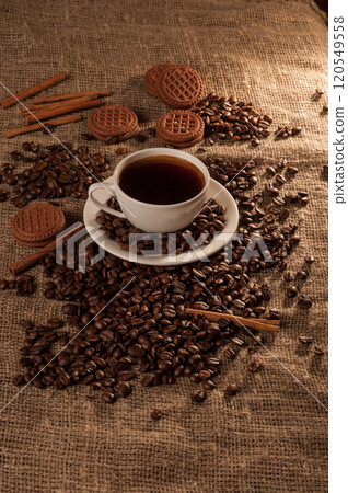 A cup of coffee on burlap and biscuits.Coffee cup with coffee bag on a wooden table. View from above. A cup of coffee on burlap and biscuits.Coffee cup with coffee bag on a wooden table. View from above. 120549558