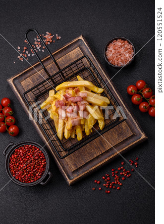 Crispy French fries with pieces of bacon, salt and spices 120551524