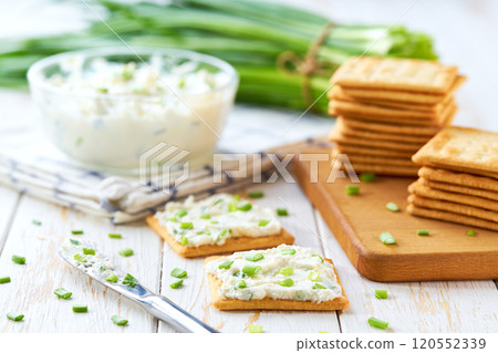 Salted biscuit with cheese cream with spring onions on a wooden table. 120552339
