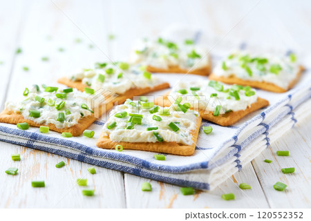 light snack of crackers with cream cheese and green onion on a blue napkin. light snack of crackers with cream cheese and green onion on a blue napkin. 120552352