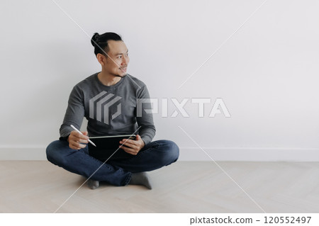 Happy creative freelance man sitting on the floor working with tablet. Happy creative freelance man sitting on the floor working with tablet. 120552497