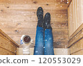 A girl in the boots with an iron mug of coffee on the terrace of a wooden house. concept 120553029