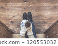 A girl in the boots with an iron mug of coffee on the terrace of a wooden house. concept 120553032
