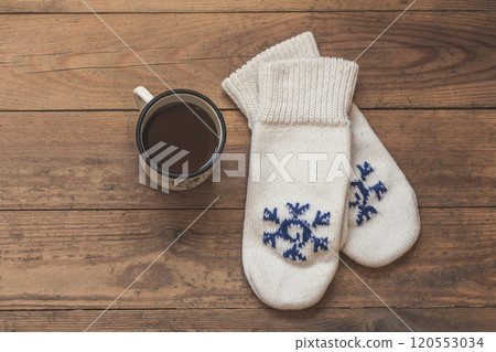 iron mug with coffee and knitted mittens on the wooden floor. Winter concept iron mug with coffee and knitted mittens on the wooden floor. Winter concept 120553034