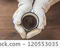 female hands  with an iron mug of coffee on the terrace of a wooden house. concept 120553035