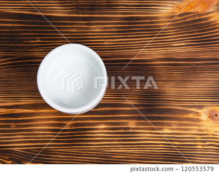 Empty white dish on dark wooden desk 120553579