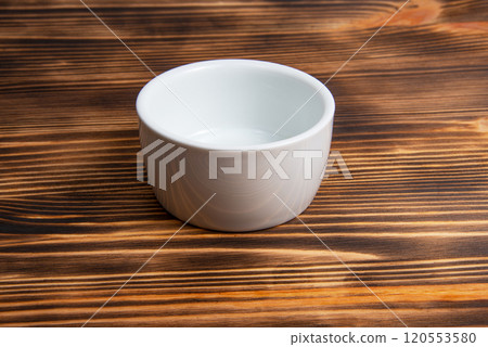 Empty white dish on dark wooden desk 120553580