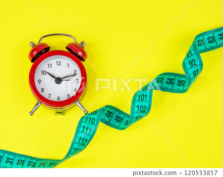 Red alarm clock and bright tape measure on yellow background with copy space 120553857