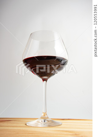Elegant wineglass with red wine on bright vintage wooden background 120553991