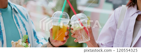 Website banner with unrecognizable couple clinking plastic cups with craft lemonade and enjoying meal 120554325