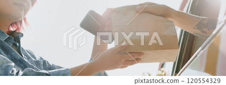 Website banner with low angle shot of unrecognizable food truck worker giving bag with order to female client 120554329