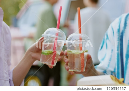 Medium close up of transparent plastic cups with sparkling craft lemonade in unrecognizable peoples hands Medium close up of transparent plastic cups with sparkling craft lemonade in unrecognizable peoples hands 120554337