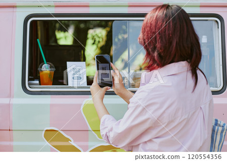 Back view shot of unrecognizable woman using smartphone to scan QR code standing on table in food truck Back view shot of unrecognizable woman using smartphone to scan QR code standing on table in food truck 120554356