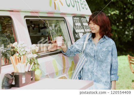 Unrecognizable male food truck worker giving order to happy Asian client who standing next to van Unrecognizable male food truck worker giving order to happy Asian client who standing next to van 120554409